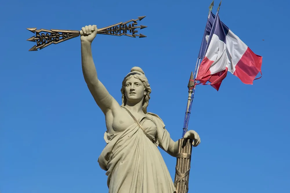 La statue de la Marianne de Villeneuve-lès-Béziers, le bras levé, le drapeau au vent